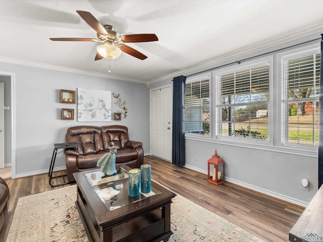 living area with a ceiling fan, crown molding, baseboards, and wood finished floors