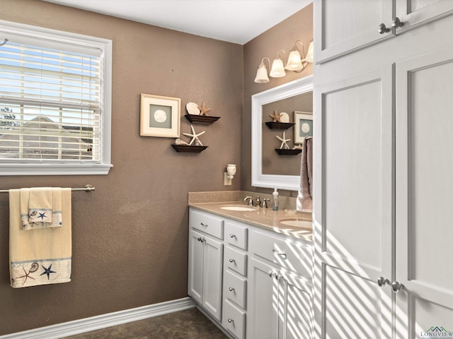 bathroom with a textured wall, vanity, and baseboards