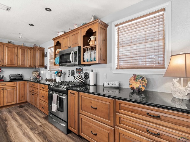 kitchen with dark wood-style floors, appliances with stainless steel finishes, a textured ceiling, and brown cabinets