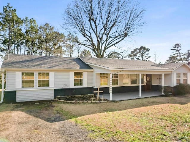 rear view of house with driveway, a patio area, and roof with shingles