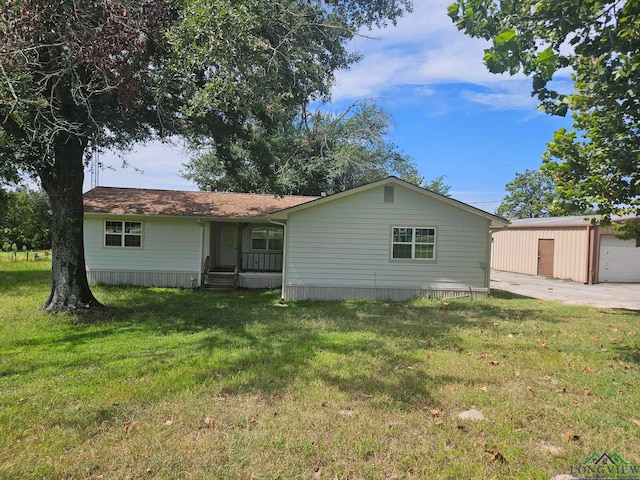 back of house featuring a garage, an outbuilding, and a yard