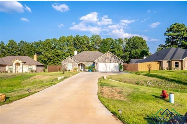 view of front facade featuring driveway, a garage, stone siding, fence, and a front yard