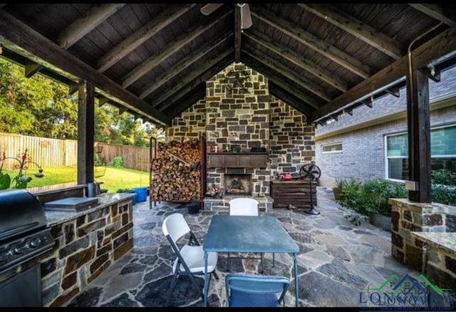 view of patio featuring an outdoor stone fireplace, area for grilling, and a fenced backyard