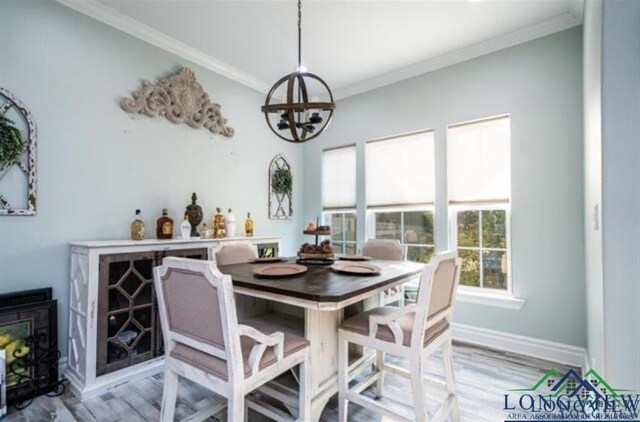 dining room featuring baseboards, light wood finished floors, an inviting chandelier, and crown molding