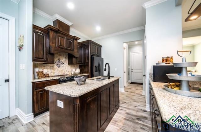 kitchen with tasteful backsplash, a center island with sink, stainless steel appliances, dark brown cabinets, and a sink