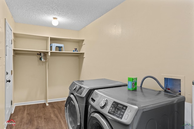 clothes washing area with wood finished floors, baseboards, laundry area, separate washer and dryer, and a textured ceiling