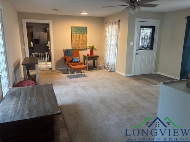 carpeted living area featuring baseboards and ceiling fan