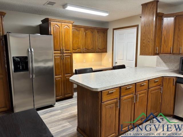 kitchen with visible vents, light countertops, brown cabinetry, and stainless steel appliances