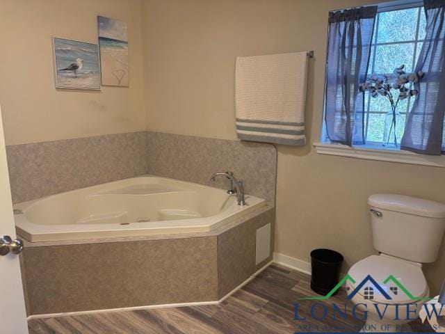 full bathroom featuring plenty of natural light, toilet, wood finished floors, and a bath