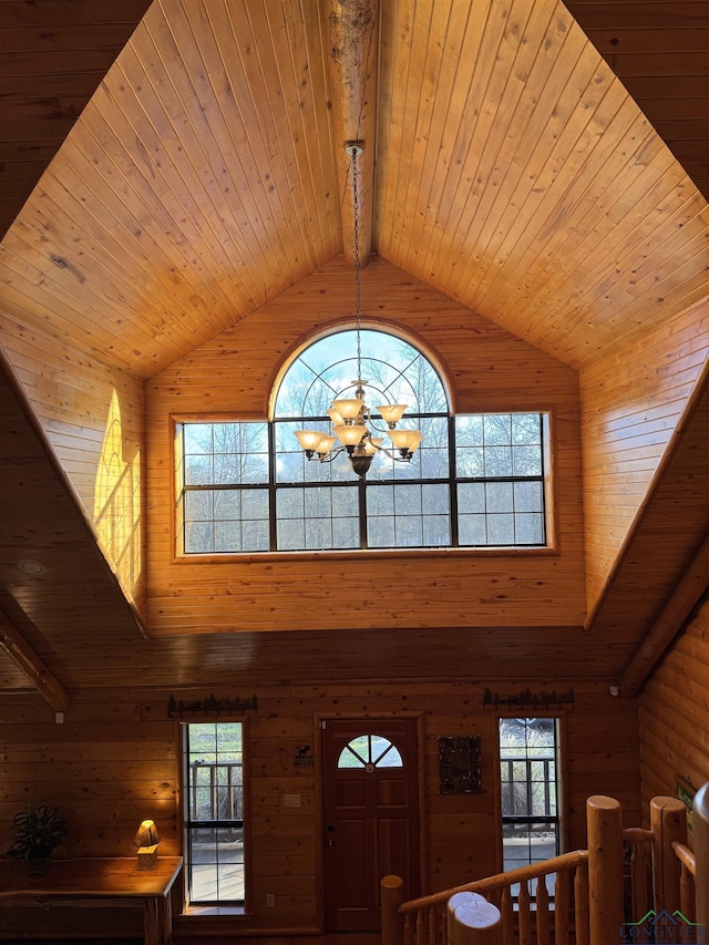 foyer with rustic walls, beam ceiling, high vaulted ceiling, wooden ceiling, and a notable chandelier