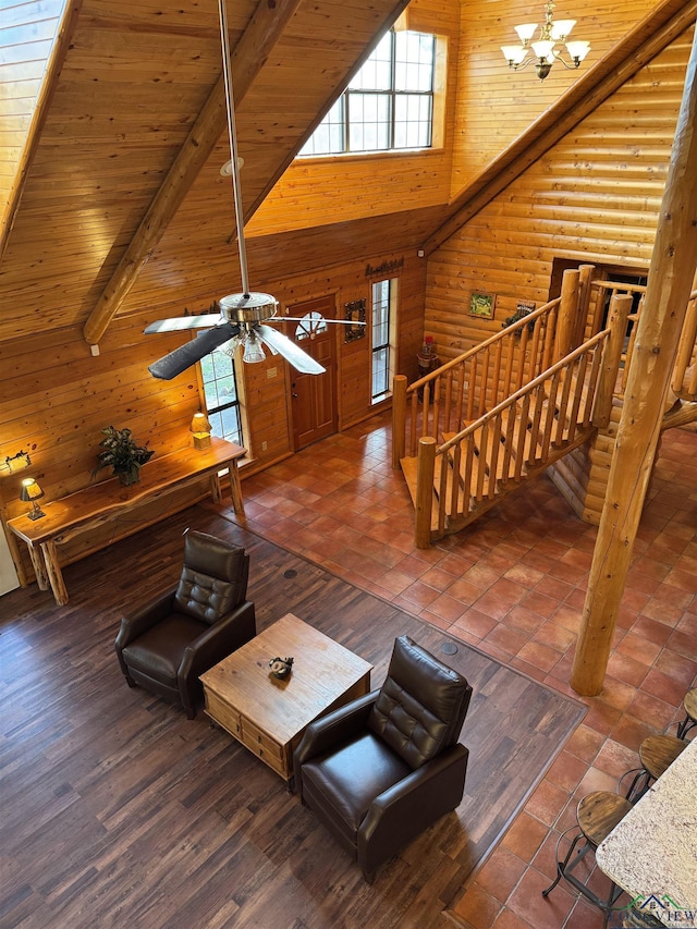 unfurnished living room with high vaulted ceiling, ceiling fan with notable chandelier, log walls, beam ceiling, and wood ceiling