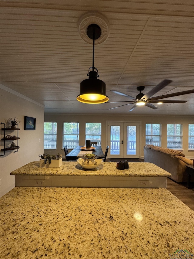 kitchen with decorative light fixtures, light stone counters, plenty of natural light, and ceiling fan