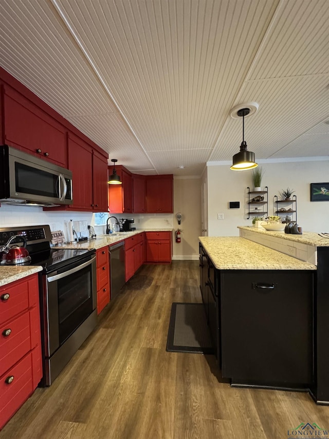 kitchen featuring sink, light stone counters, appliances with stainless steel finishes, decorative light fixtures, and dark hardwood / wood-style flooring