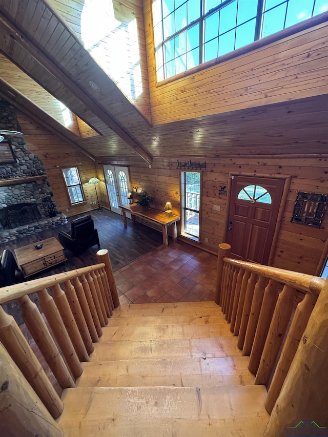 stairway featuring wood-type flooring, a high ceiling, wood walls, and wood ceiling