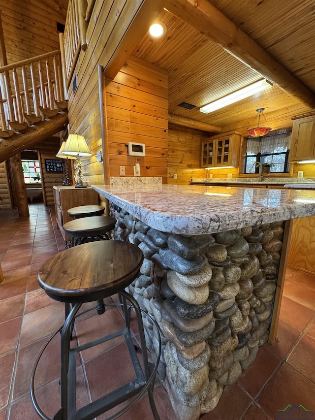 bar featuring beam ceiling, light stone countertops, decorative light fixtures, wooden walls, and wood ceiling