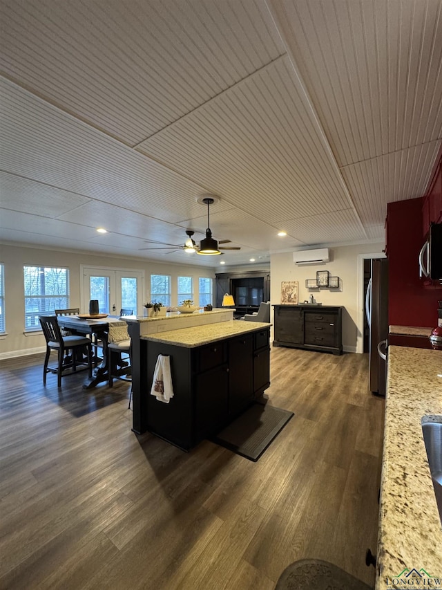 kitchen featuring stainless steel appliances, a wall mounted AC, dark wood-type flooring, ceiling fan, and a center island