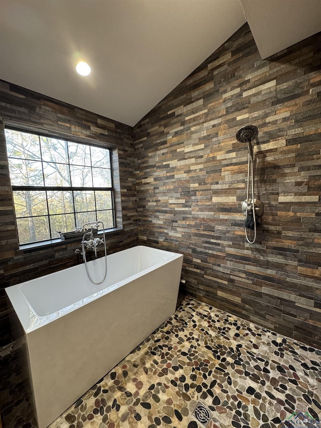 bathroom featuring a tub to relax in and lofted ceiling