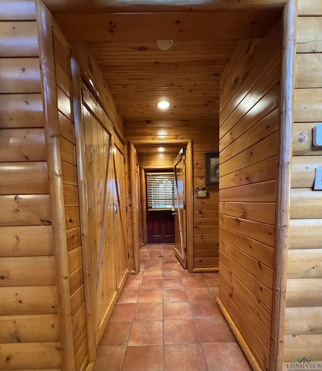 hall featuring light tile patterned flooring, wooden ceiling, and wood walls