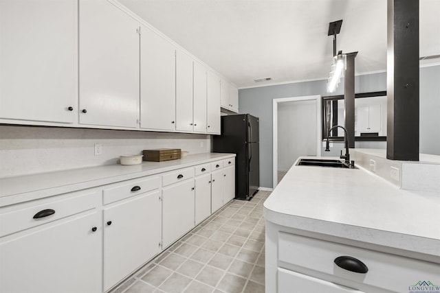 616 Cynthia St, Longview, TX 75605 - kitchen featuring a sink, freestanding refrigerator, light countertops, ornamental molding, and white cabinets