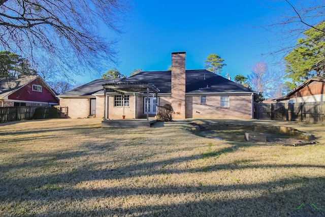 rear view of property with a lawn, a pergola, fence, brick siding, and a chimney