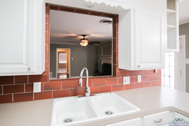 kitchen with visible vents, a ceiling fan, a sink, backsplash, and white cabinetry