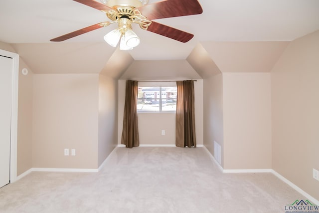 additional living space featuring visible vents, light carpet, baseboards, ceiling fan, and vaulted ceiling