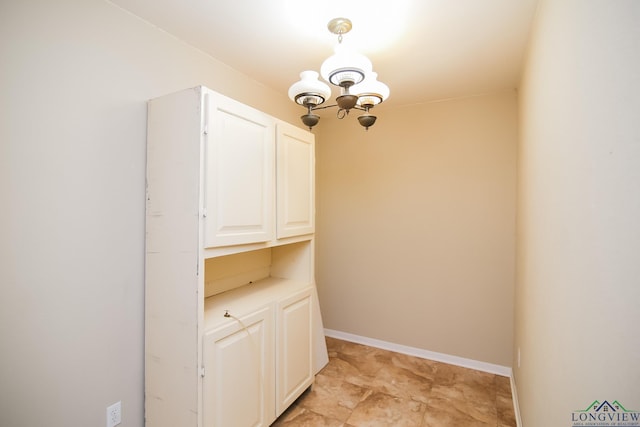 unfurnished dining area featuring baseboards and an inviting chandelier