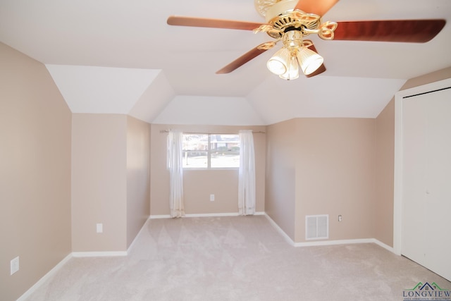 interior space featuring visible vents, light colored carpet, baseboards, and lofted ceiling