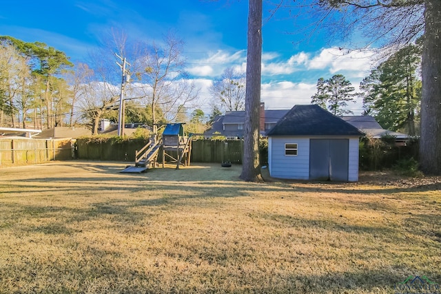 view of yard with a storage unit, an outbuilding, a fenced backyard, and a playground