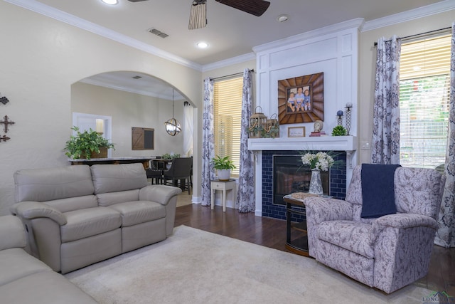 living room with a tiled fireplace, ceiling fan, ornamental molding, and hardwood / wood-style flooring