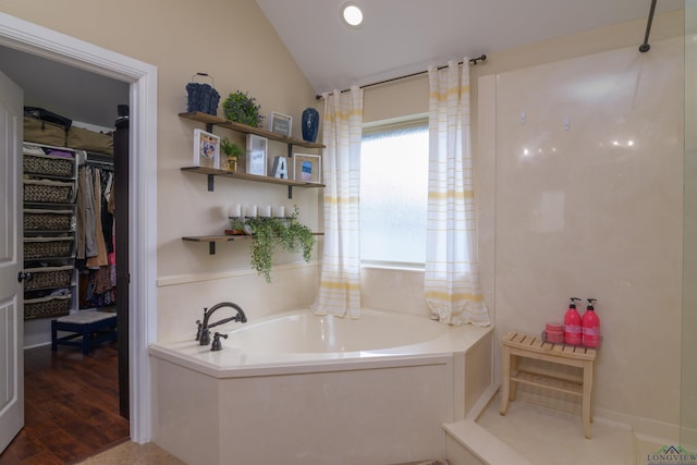 bathroom featuring hardwood / wood-style floors, a tub to relax in, and vaulted ceiling