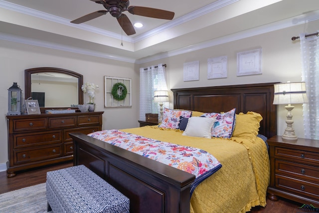 bedroom with a raised ceiling, ceiling fan, dark wood-type flooring, and ornamental molding