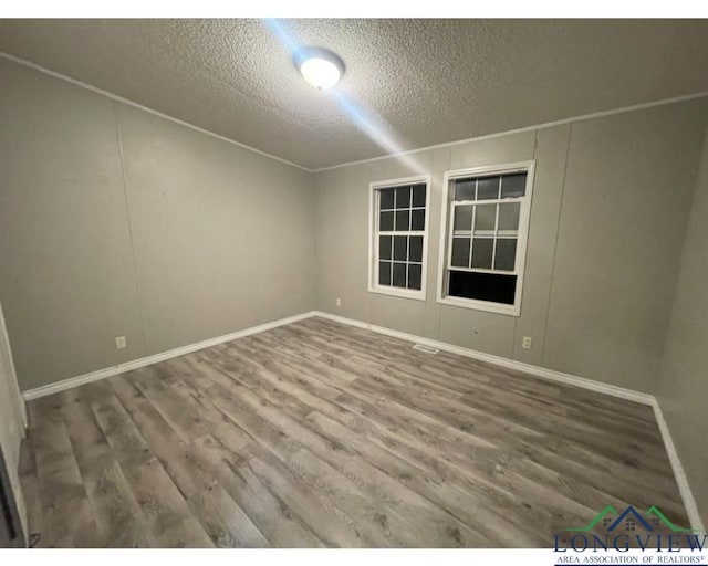 spare room featuring a textured ceiling and hardwood / wood-style flooring