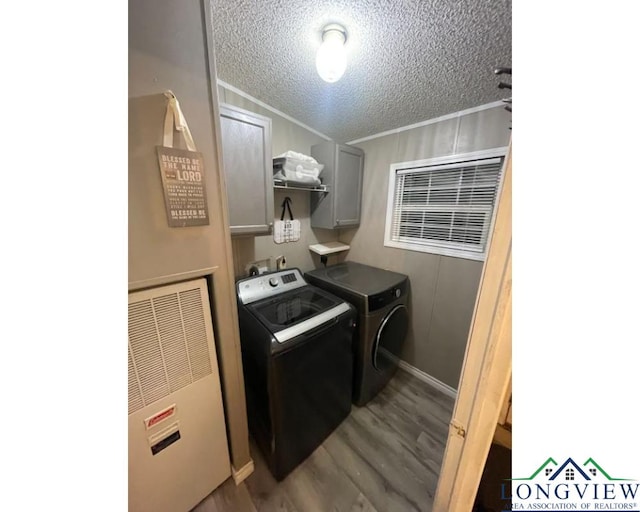 laundry area with cabinets, wood-type flooring, a textured ceiling, and washer and clothes dryer