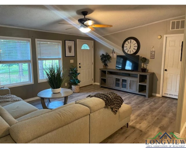 living room with a textured ceiling, hardwood / wood-style flooring, ceiling fan, and ornamental molding