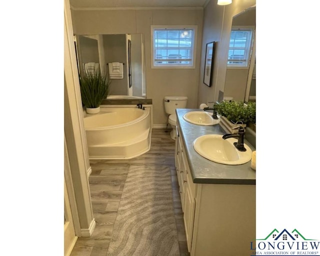 bathroom featuring ornamental molding, vanity, a bath, hardwood / wood-style floors, and toilet