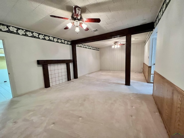 basement with wooden walls, ceiling fan, and light carpet