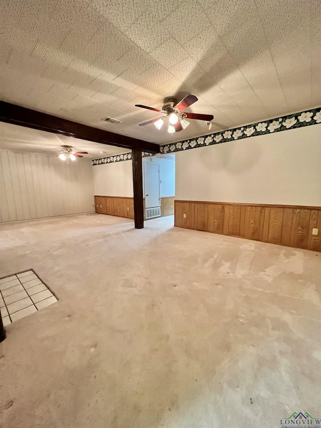 basement featuring wooden walls, carpet floors, and ceiling fan