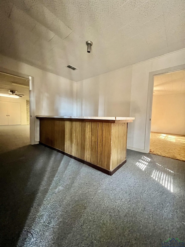 bar with ceiling fan, a textured ceiling, and dark colored carpet