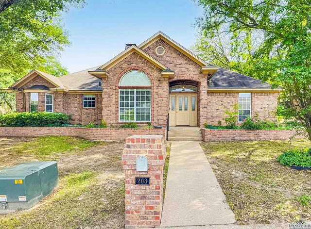 ranch-style house featuring brick siding and a shingled roof