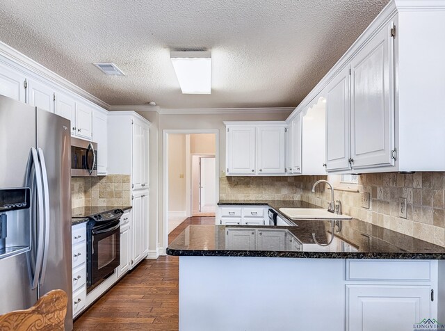 kitchen with dark wood-style flooring, appliances with stainless steel finishes, a sink, white cabinets, and a peninsula