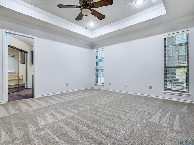 carpeted empty room featuring crown molding, baseboards, ceiling fan, and a tray ceiling