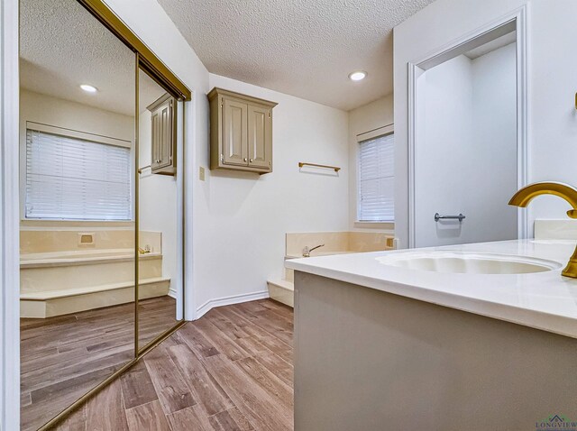 bathroom featuring vanity, a tub to relax in, a textured ceiling, and wood finished floors