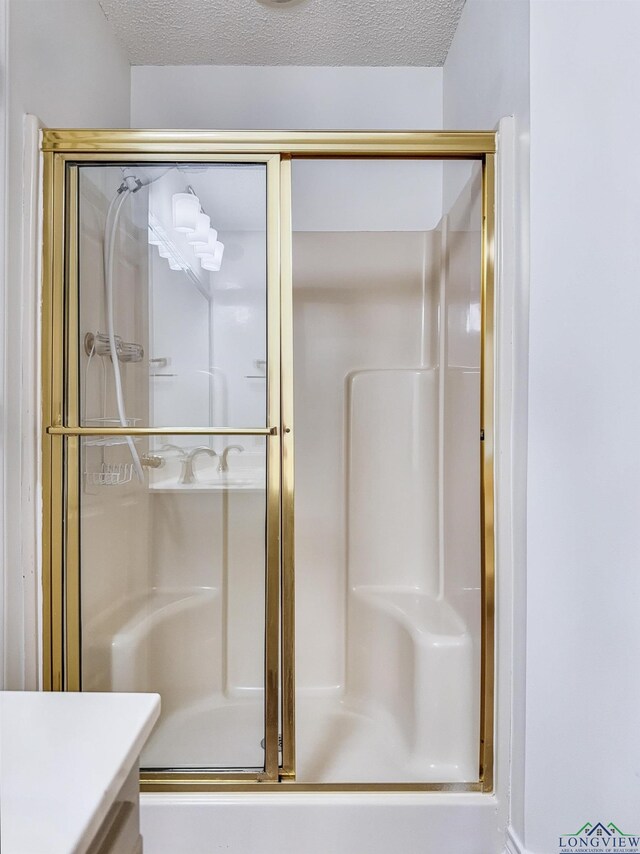 full bath featuring an enclosed shower, vanity, and a textured ceiling