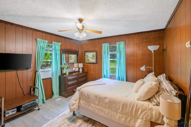 350 Capri St, Ore City, TX 75683 - bedroom with light wood-style floors, a textured ceiling, wood walls, ceiling fan, and ornamental molding