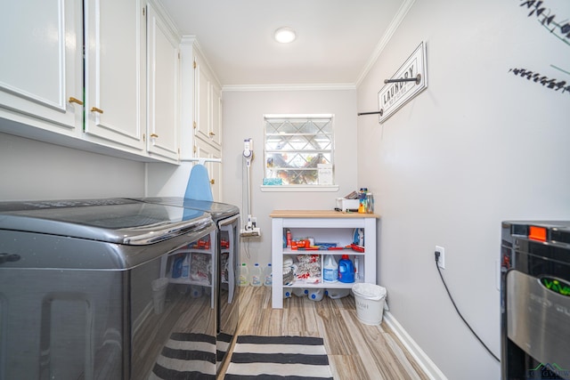 laundry area with cabinets, light wood-type flooring, crown molding, and washing machine and dryer