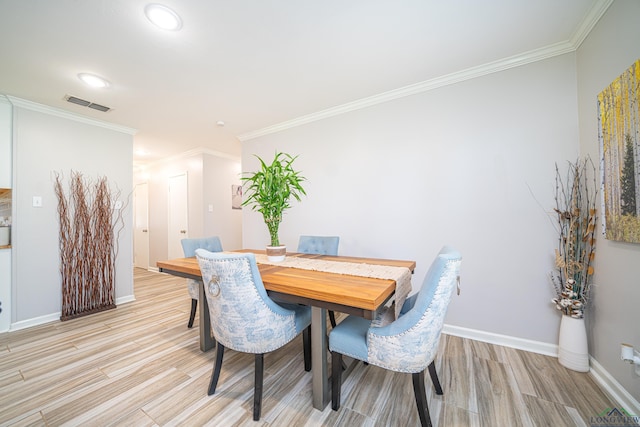 dining area featuring light wood-type flooring and crown molding