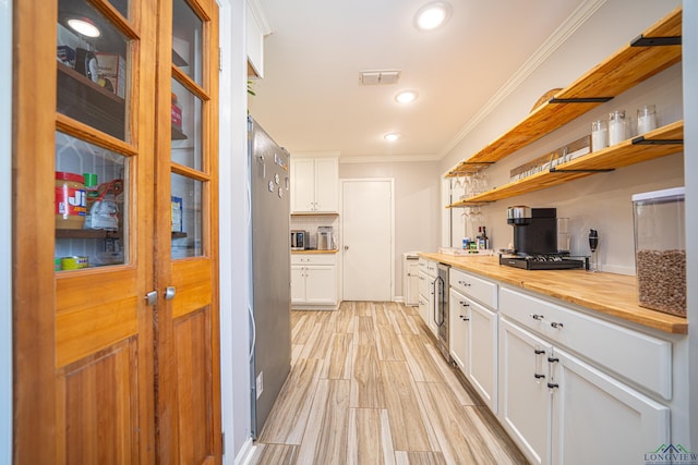 kitchen featuring stainless steel refrigerator, white cabinetry, ornamental molding, decorative backsplash, and light wood-type flooring