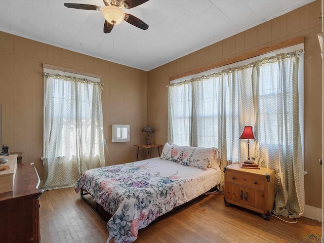 bedroom with ceiling fan, wood finished floors, and ornamental molding