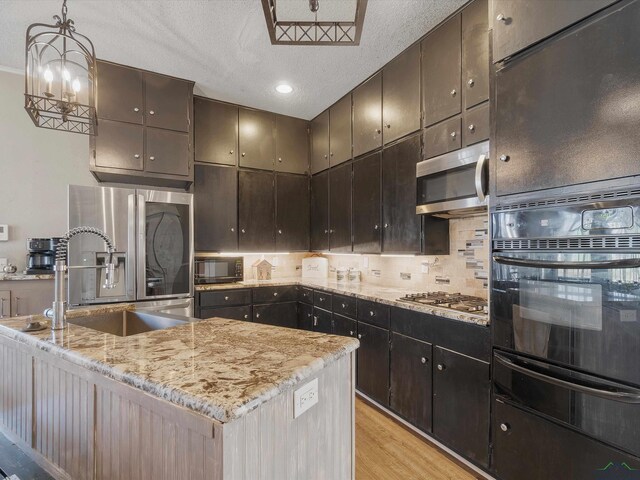 kitchen featuring a warming drawer, a sink, light wood-style floors, appliances with stainless steel finishes, and decorative backsplash